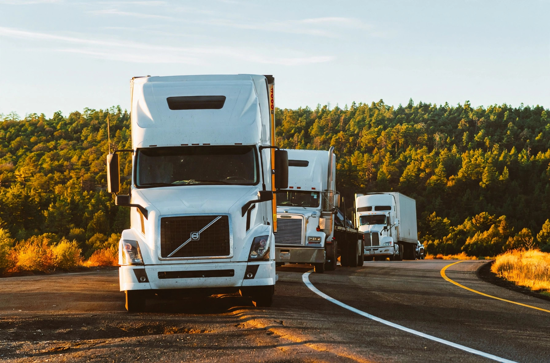Semi trucks on a highway at sunset